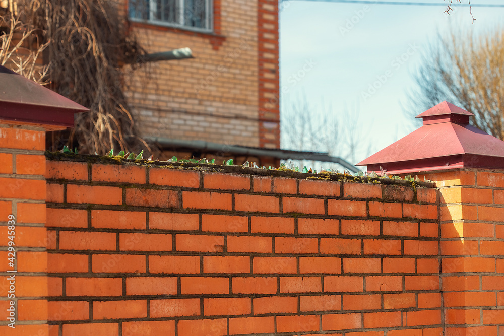 Broken glass glued to cement on top of a brick fence in a village Broken glass glued to cement on top of a brick fence in a village