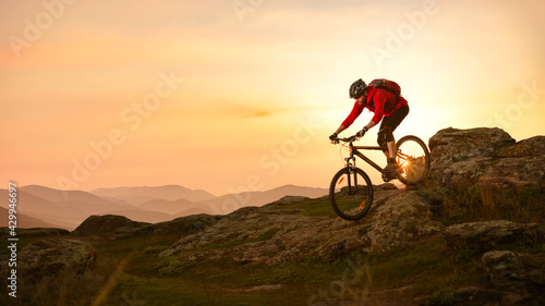Cyclist in Red Riding Bike on the Summer Rocky Trail at Sunset. Extreme Sport and Enduro Biking Concept.