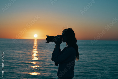photographer with a camera at sunset near the sea