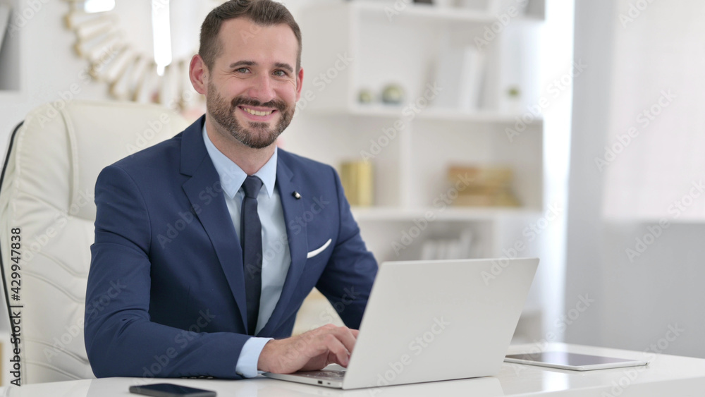 Fototapeta premium Cheerful Businessman with Laptop Smiling at the Camera 