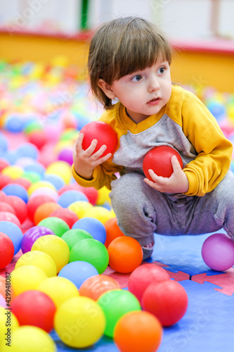 Creative development of children. The kid plays with colored balls in the children's development center.