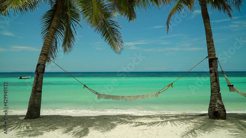 Beautiful tropical island with sand beach and hammock. Panglao, Philippines. Seascape with beautiful beach and palm trees.