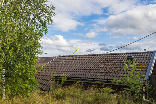 View of dark grey old tiled roof on blue sky background. Beautiful backgrounds.