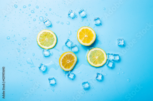 juicy fresh lemon slices and ice cubes on a blue background. Top view, flat lay