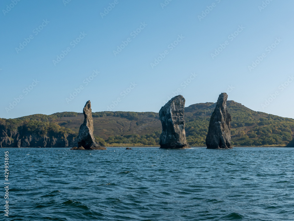 Exit on a yacht to the Avacha Bay of the Pacific Ocean. View of the rocks three brothers are a symbol of Avacha Bay and the city of Petropavlovsk-Kamchatsky. Kamchatka Peninsula, Russia.