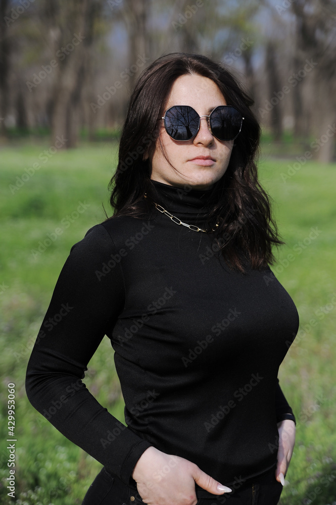 Beautiful young woman in sunglasses enjoying the spring. Woman lying in the grass outdoors. Beautiful young woman in sunglasses enjoying the spring. Woman lying in the grass outdoors.