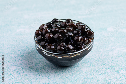 Tableau sur toile Glass bowl of black tapioca pearl bubbles on the blue background