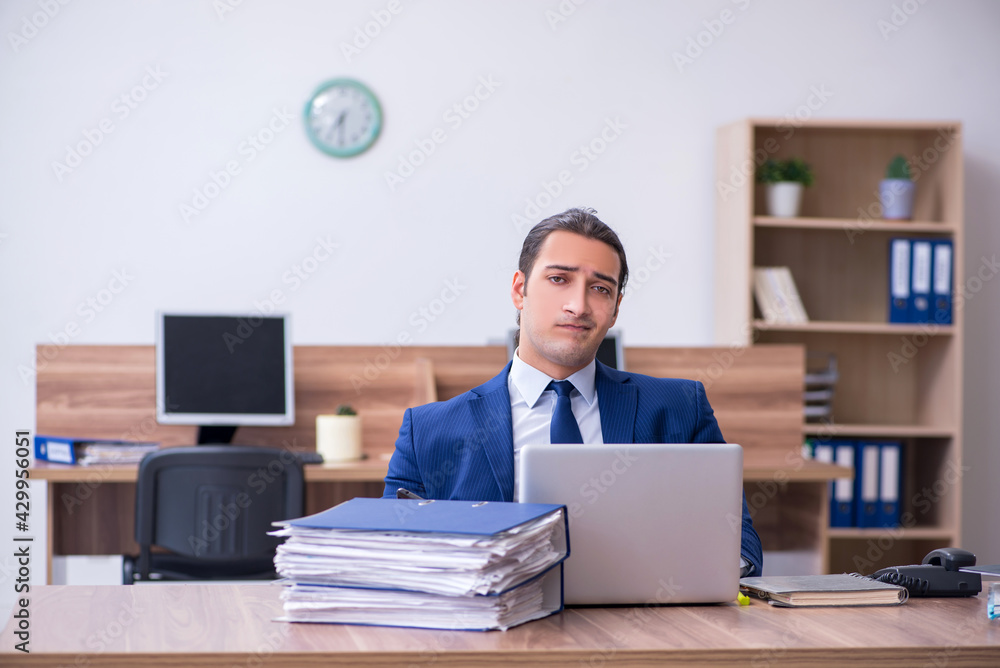 Young male employee unhappy with excessive work Young male employee unhappy with excessive work