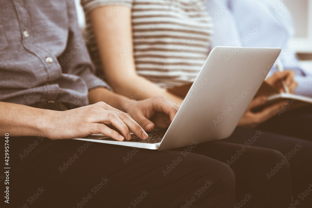 Group of casual dressed business people working at meeting or conference, close-up of hands. Businessman using laptop computer. Teamwork or coaching concept Group of casual dressed business people working at meeting or conference, close-up of hands. Businessman using laptop computer. Teamwork or coaching concept