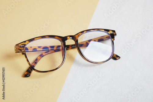 stylish glasses on beige and gray background copy space