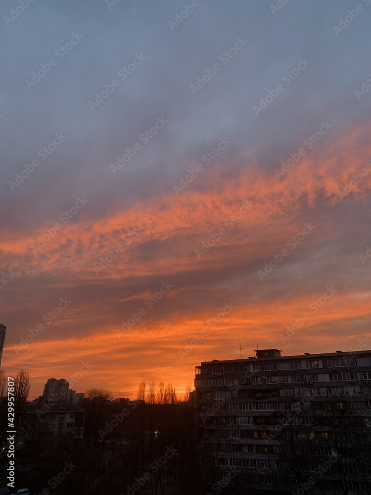Rooftop view of sunset in Kyiv, Ukraine. Orange, yellow, pink and red sunset. Lifestyle and city tranquility concept. High quality vertical photo