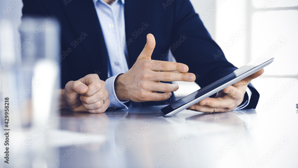 Business people using tablet computer while working together at the desk in modern office. Unknown businessman or male entrepreneur with colleague at workplace. Teamwork and partnership concept Business people using tablet computer while working together at the desk in modern office. Unknown businessman or male entrepreneur with colleague at workplace. Teamwork and partnership concept