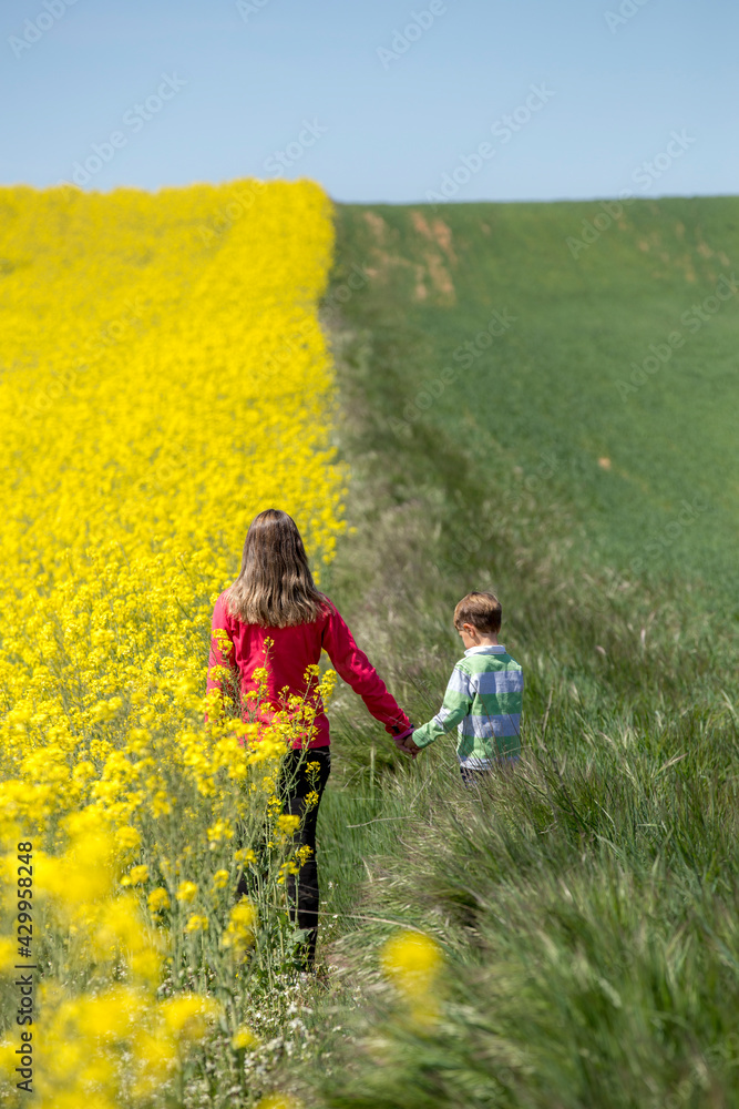 Madre e hijo disfrutando en los campos de colza amarillos