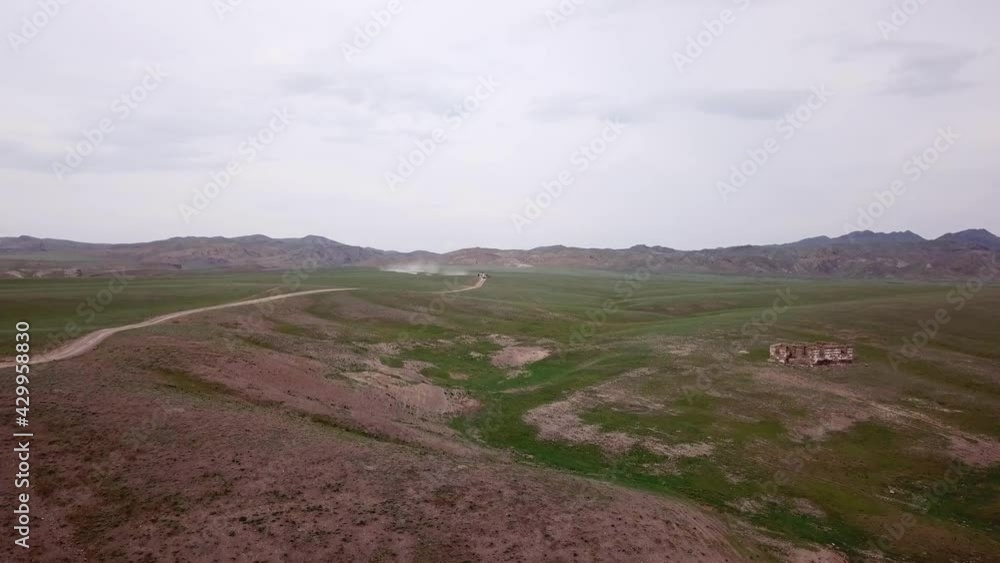 View of green hills and gorges with rocks. In the distance you can see the mountains, the river, the road. Hills covered with grass. Small gorges. Pure nature. Top view from the drone. Kazakhstan. View of green hills and gorges with rocks. In the distance you can see the mountains, the river, the road. Hills covered with grass. Small gorges. Pure nature. Top view from the drone. Kazakhstan.