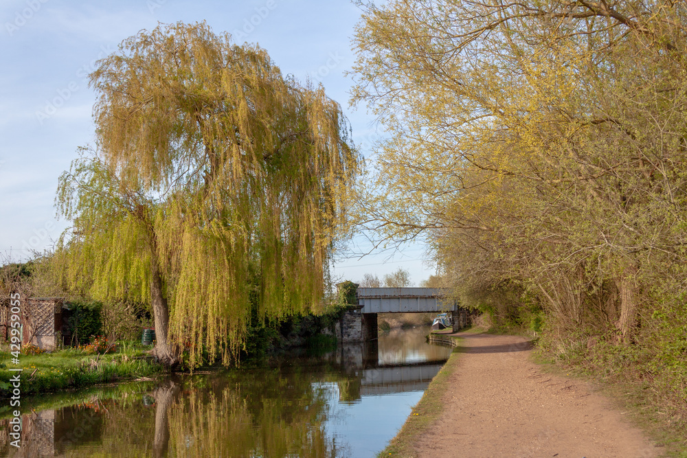 Willington. Derbyshire, UK, April,23,2021: A picturesque scene on the Trent and Mersey Canal near Willington, showing a railway viaduct and trees in a rural setting.