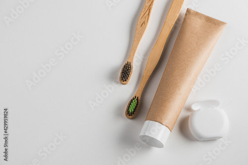 Top view on wooden toothbrushes, toothpaste and dental floss on white background
