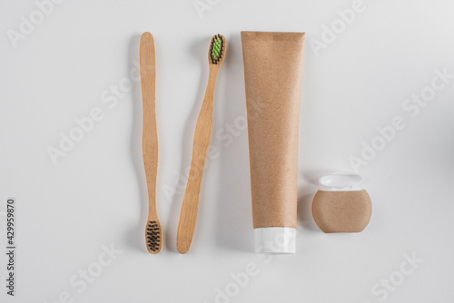 Top view on bamboo toothbrushes, toothpaste and dental floss on white background
