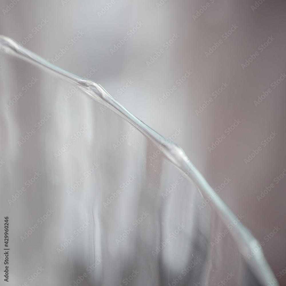 Der gewellte Rand eines Glases bildet ein grafisches Element in einem Quadrat. Der gewellte Rand eines Glases bildet ein grafisches Element in einem Quadrat.