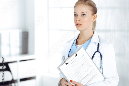 Woman - doctor standing in clinic. Physician at work, studio portrait. Medicine and health care concept