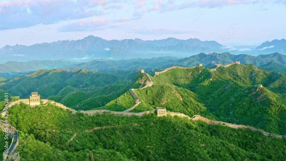 Aerial shot of winding Great Wall of China and surrounding green mountain Aerial shot of winding Great Wall of China and surrounding green mountain
