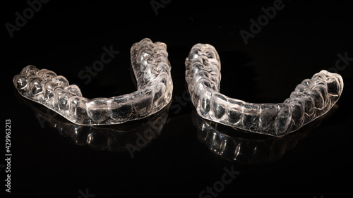 Removable plastic retainers for bite correction on a black background photo