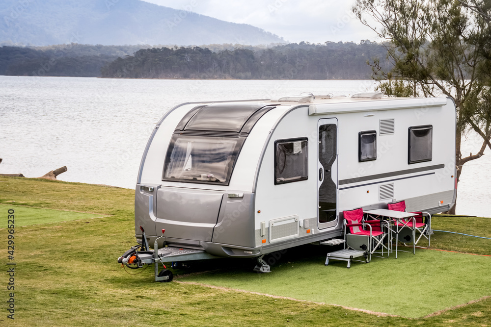 RV caravan camping at the caravan park on the lake with mountains on the horizon. Camping vacation travel concept - obrazy, fototapety, plakaty 