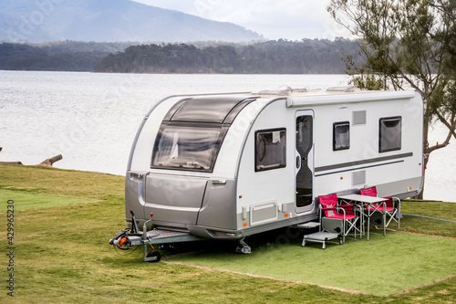 Fototapet RV caravan camping at the caravan park on the lake with mountains on the horizon
