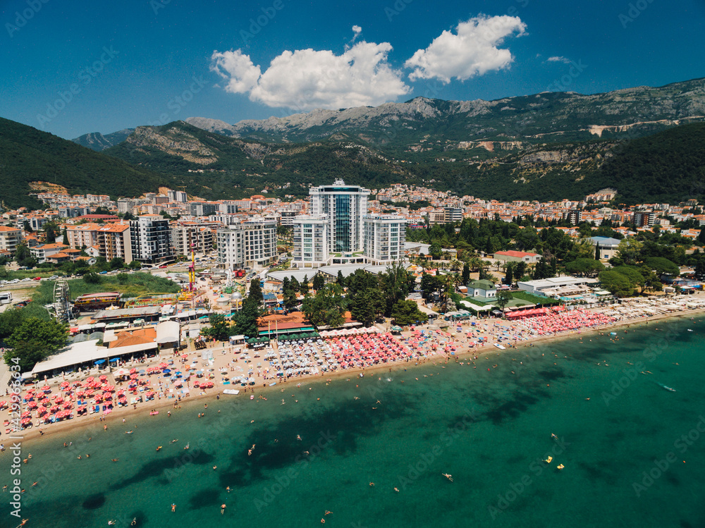 Aerial view of the beach in Budva against the backdrop of modern buildings and green mountains