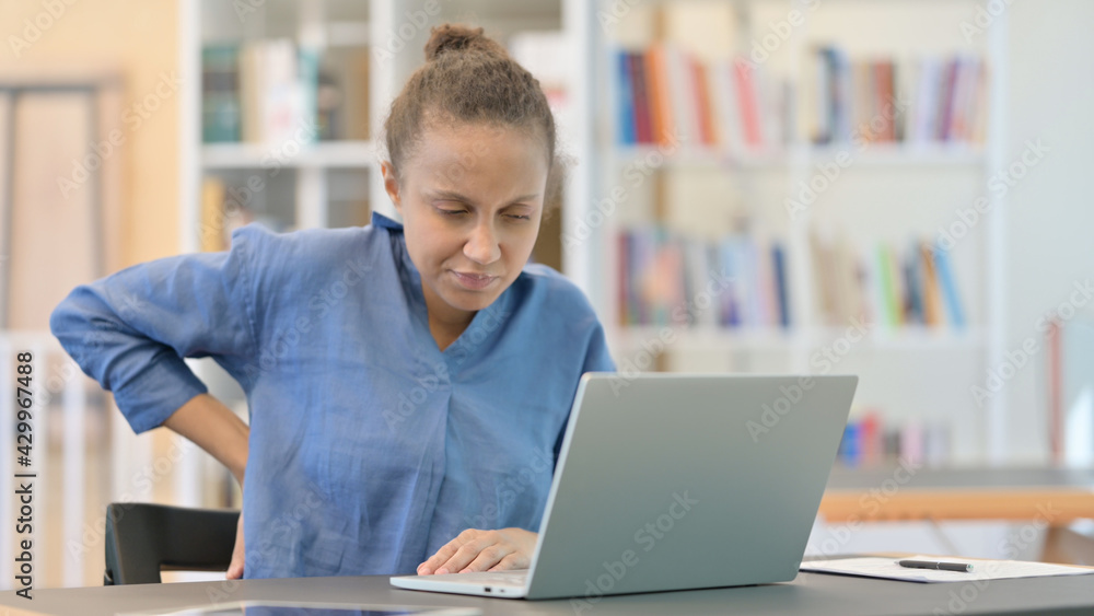 Tired African Woman with Laptop having Back Pain in Library Tired African Woman with Laptop having Back Pain in Library