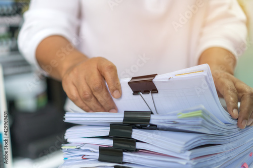 Office workers arranging stacks of lot documents report papers with clips waiting be managed on desk in busy office. Concept of workload in business finacial paperwork information planing