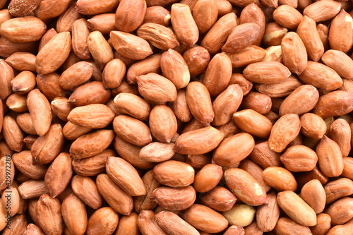Many grains of organic peeled peanuts, close-up, top view.