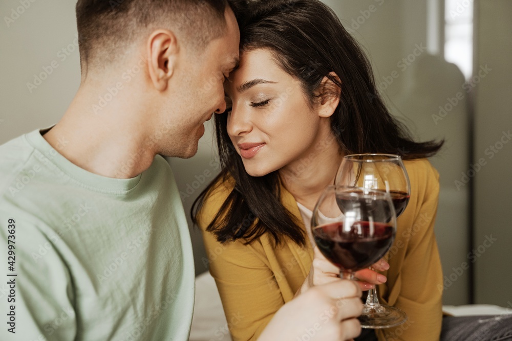 Lovely couple with glasses of wine has romantic dinner at home. Happy young family moved to new apartment Lovely couple with glasses of wine has romantic dinner at home. Happy young family moved to new apartment