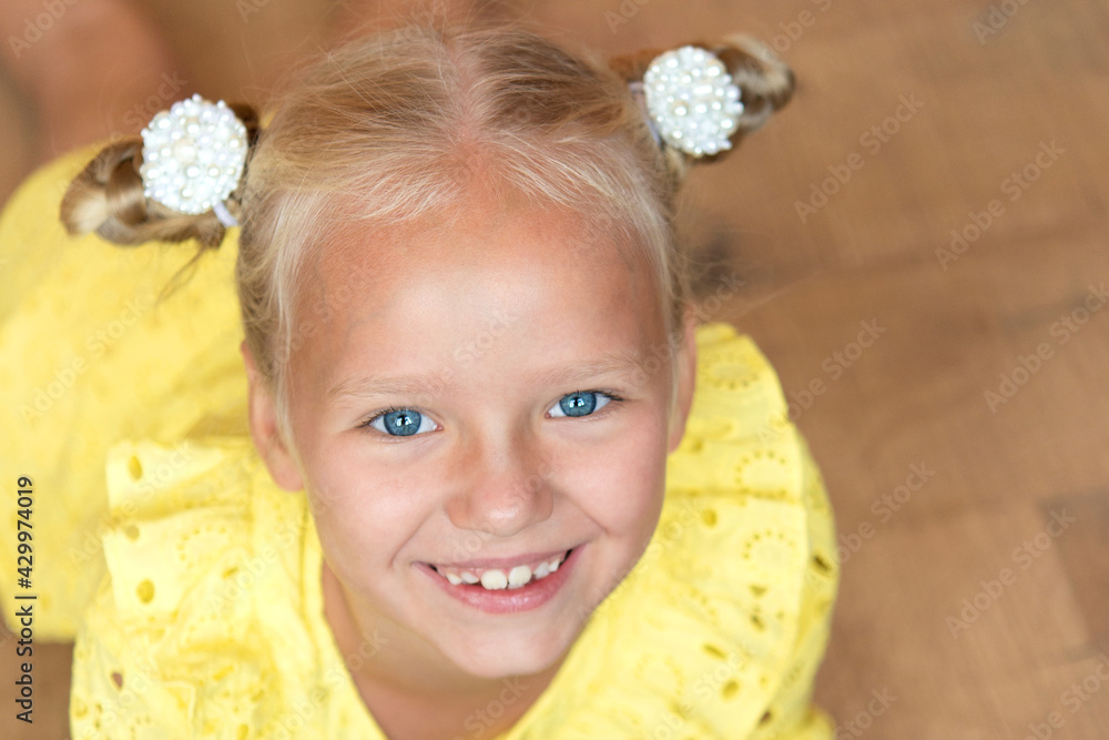 cute little blonde with bright emotions - a wide smile with open teeth. She is wearing a simple yellow dress. European race. cute little blonde with bright emotions - a wide smile with open teeth. She is wearing a simple yellow dress. European race.