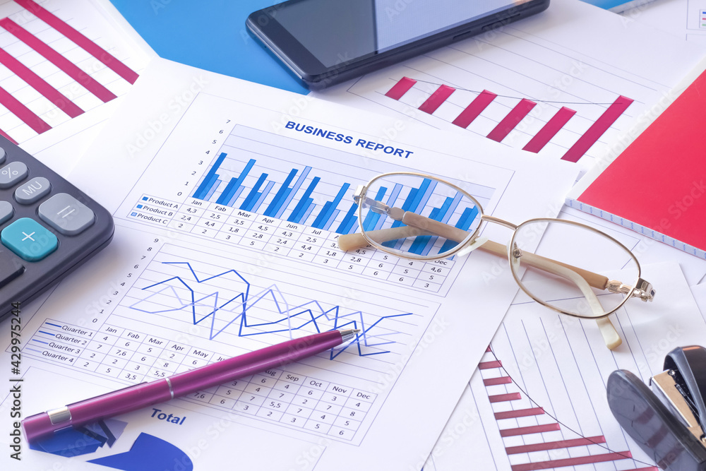 Business graphs, charts, data tables, business report, pen, glasses, calculator, smartphone. Business graphs, charts, data tables, business report, pen, glasses, calculator, smartphone.