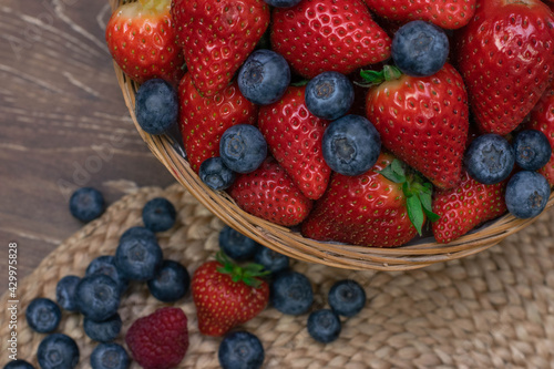 Strawberry and blueberry in basket on wood table. Close up berries.