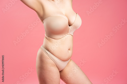 Sexy woman with very large breasts in a push-up bra on pink background, perfect female body