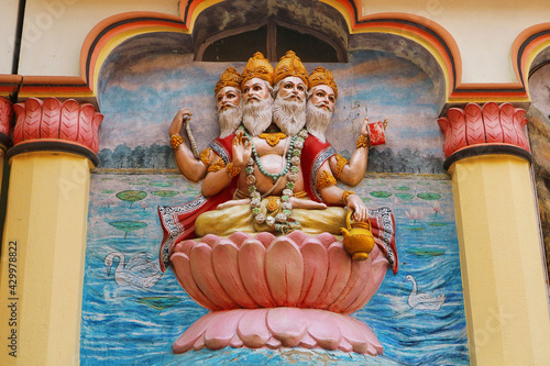 View of wall art of Hindu god Brahma. Brahma, the four-headed lord, sits on a lotus flower. Religious image on the temple in India. photo