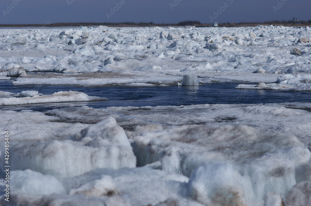 Ice hummocks on the river in spring. There is a funnel on the water in the sharpness zone.