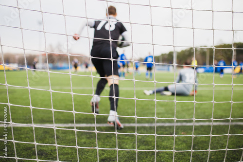 Football goal - player takes the ball out of the goal and runs towards the center - Football goal net on a blurred background of a soccer match