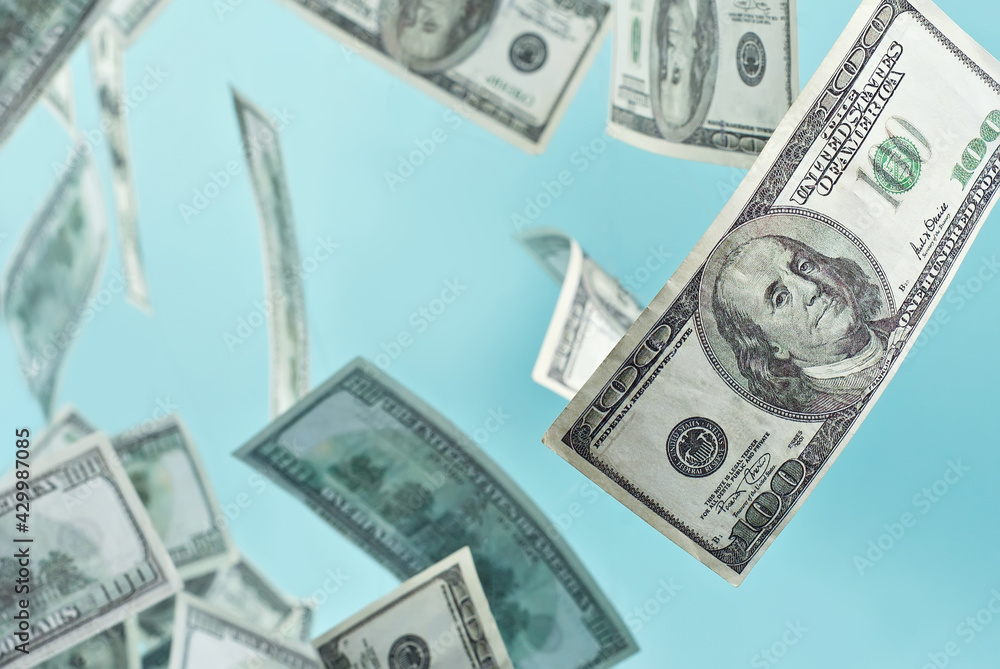Green dollar bills on a blue background. 100 dollar bills close up. The concept of wealth and success. Money flies in the air. Green dollar bills on a blue background. 100 dollar bills close up. The concept of wealth and success. Money flies in the air.