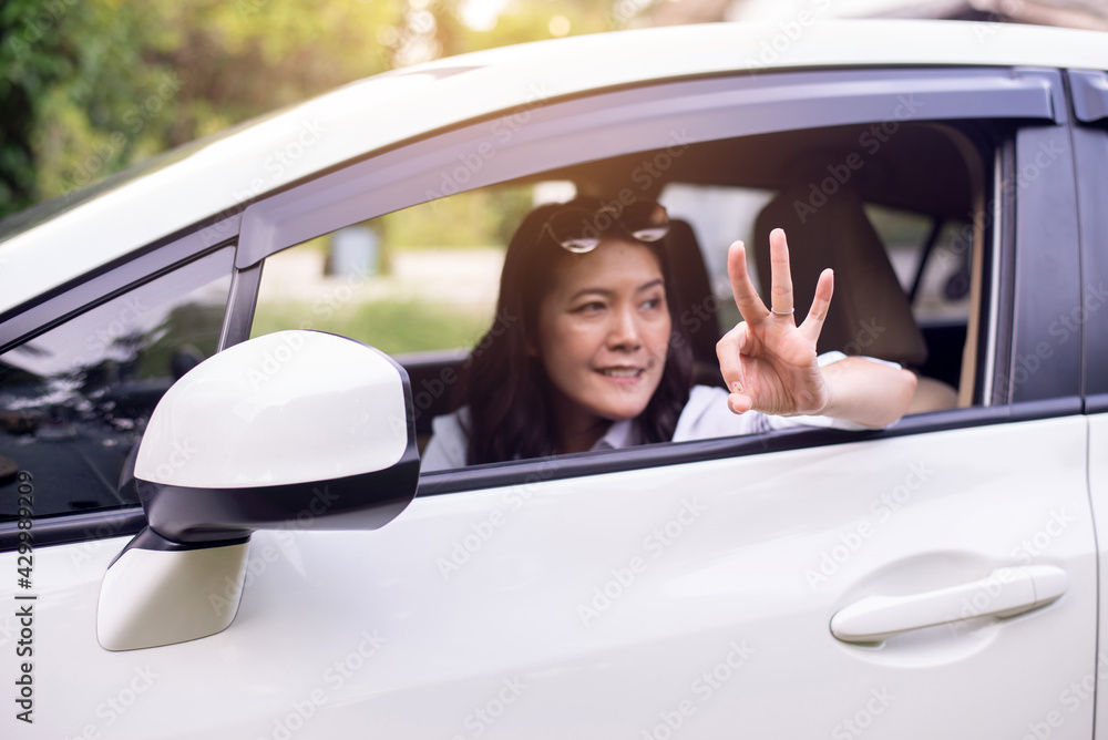 Happy asian woman showing ok sign while sitting in the car looking out windows,Car insurance concept Happy asian woman showing ok sign while sitting in the car looking out windows,Car insurance concept
