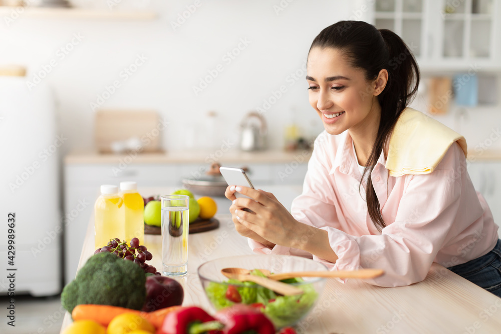 Portrait of smiling young woman using cellphone in kitchen Portrait of smiling young woman using cellphone in kitchen