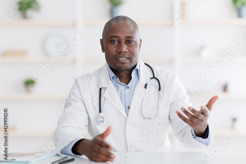Patient s point of view of medical consultation. Black male doctor gesturing to camera in his office