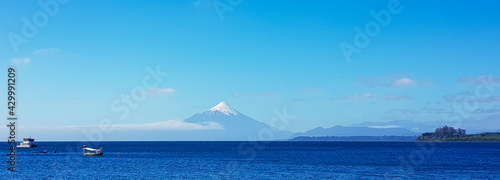 Retrato de volcán junto a 2 barcos en medio del mar