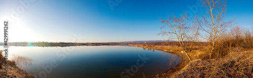 Panoramic view of a calm lake on a sunny summer day © mikhailgrytsiv