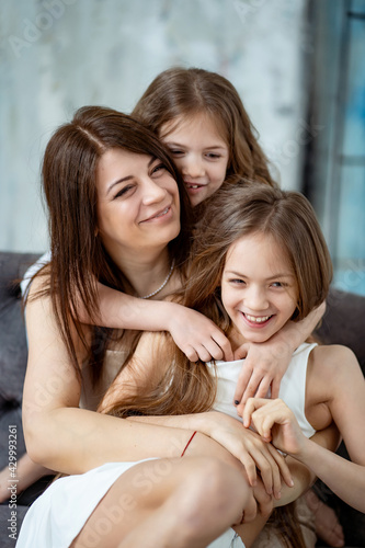 Mom cuddles with her daughters. happy family. 