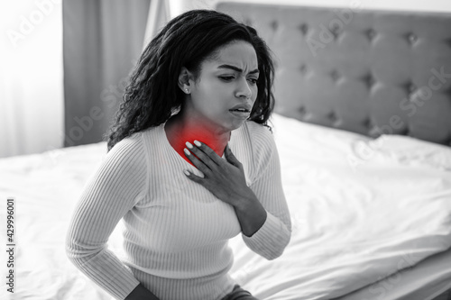 Young black woman coughing, suffering from sore throat photo