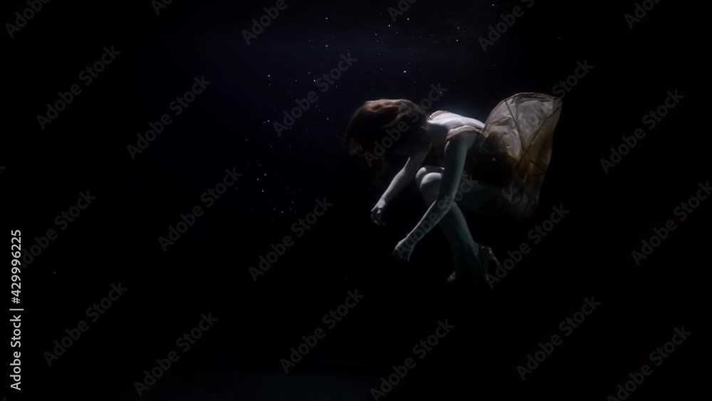 mysterious underwater shot of sinking female body in dark deepness ...