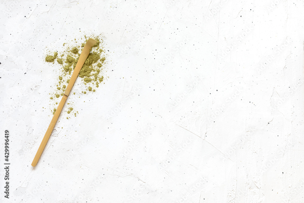 spoon with scattered dry matcha tea powder and whisk on white background spoon with scattered dry matcha tea powder and whisk on white background