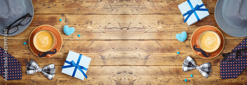Happy Fathers day concept with coffee cup, mustache, hat, necktie and gift box on wooden background